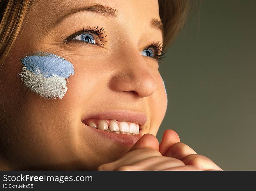 Portrait of a woman with the flag of the Argentina painted on her face.