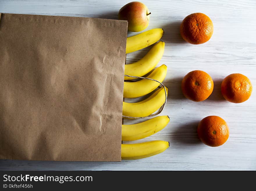 Paper bag of different fruits on white wooden background. Flat lay