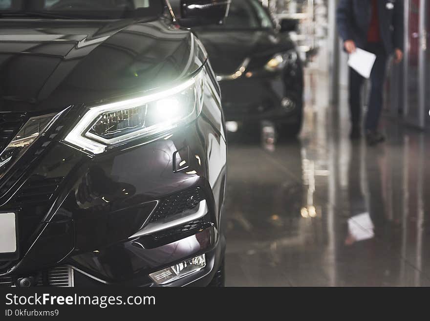 The headlights and the hood of a black luxury car.