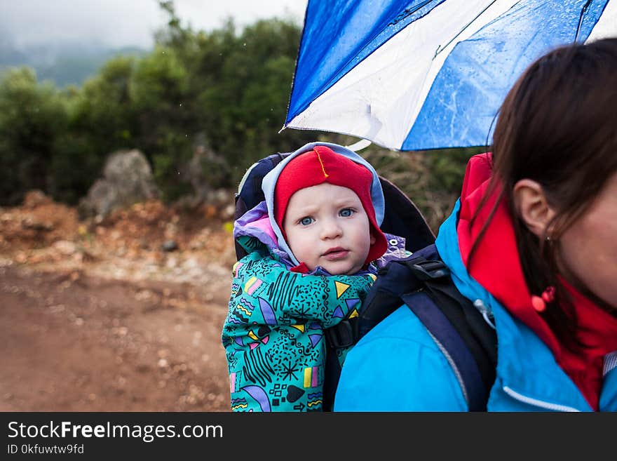 A woman carries a child in a backpack.