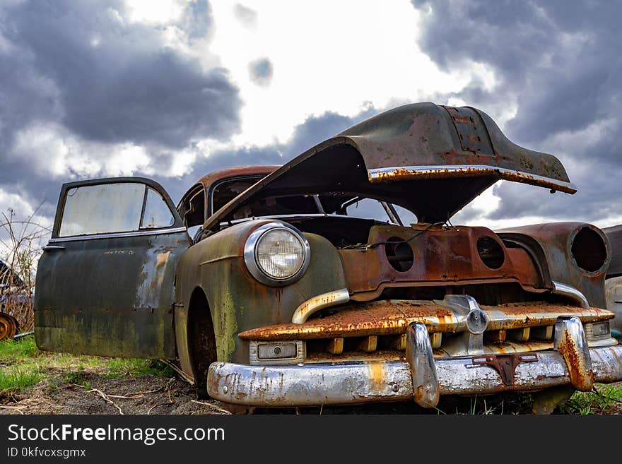 Old car waiting for a rebuild. Low angle view of an old car against a dramatic sky with room for copy. Old car waiting for a rebuild. Low angle view of an old car against a dramatic sky with room for copy