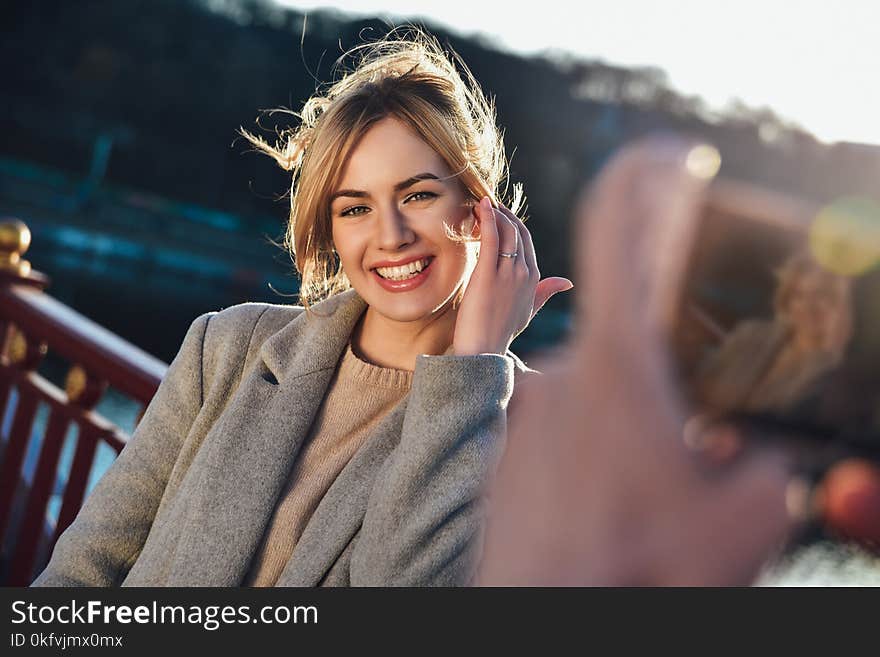 A man make a portrait of happy smiling woman standing on the bridge on sunny summer or spring day outdoor. A man make a portrait of happy smiling woman standing on the bridge on sunny summer or spring day outdoor