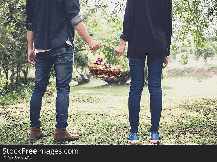 Couple in love walking and holding a picnic basket on nature out