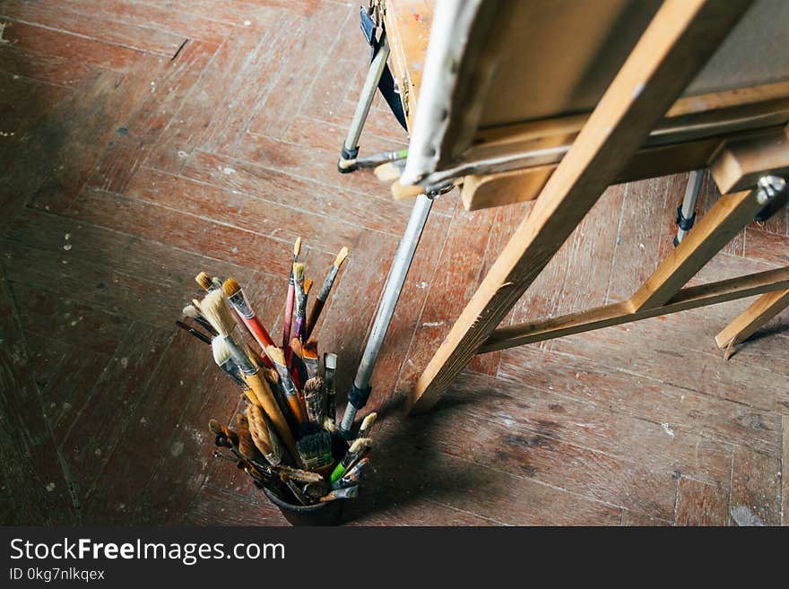 Brushes of different density and size for drawing on an old wooden easel, stand on the floor. Brushes of different density and size for drawing on an old wooden easel, stand on the floor