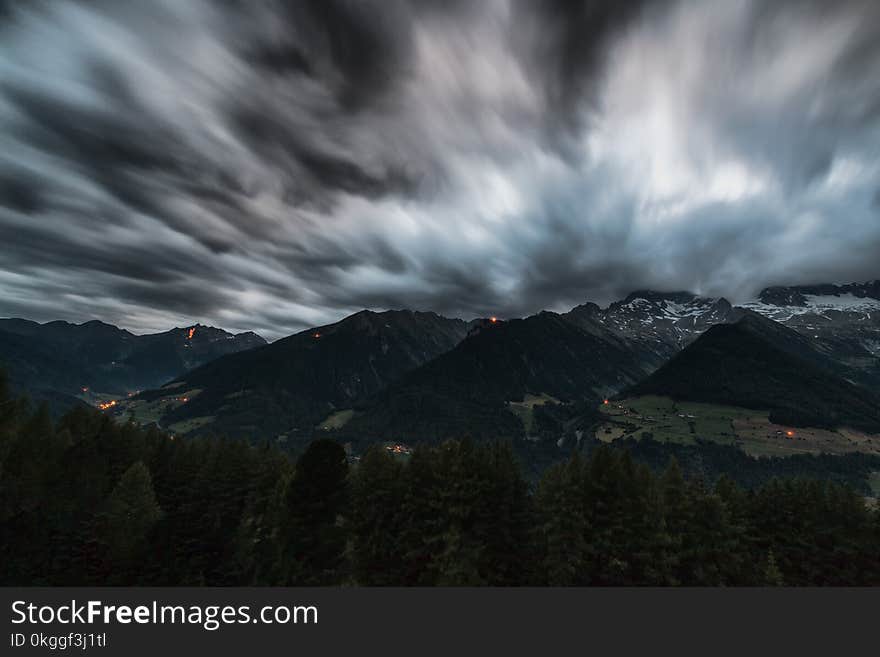 Time Lapse Photography of Pine Trees Near Mountains Under Grey Clouds