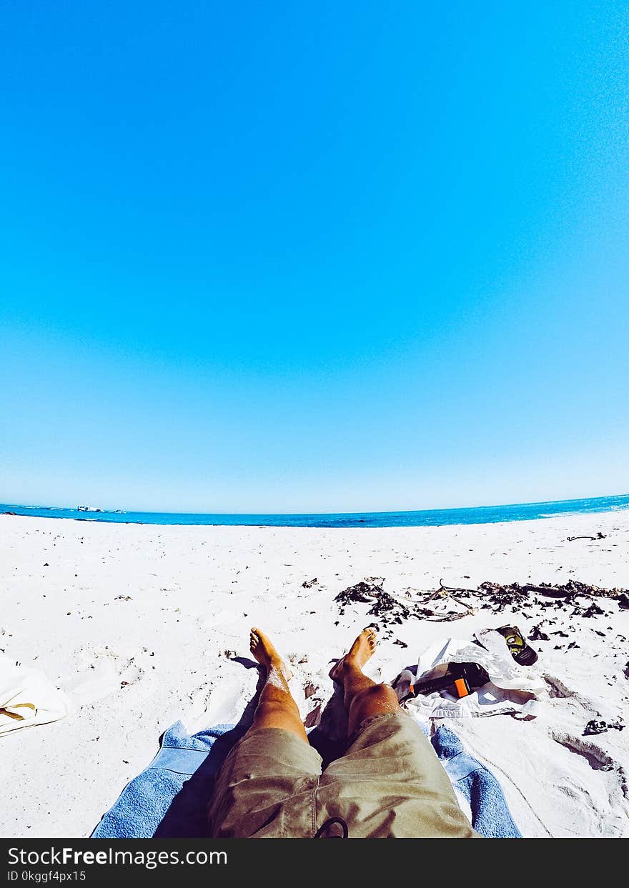 Man in Gray Shorts Laying on White Sand in Beach