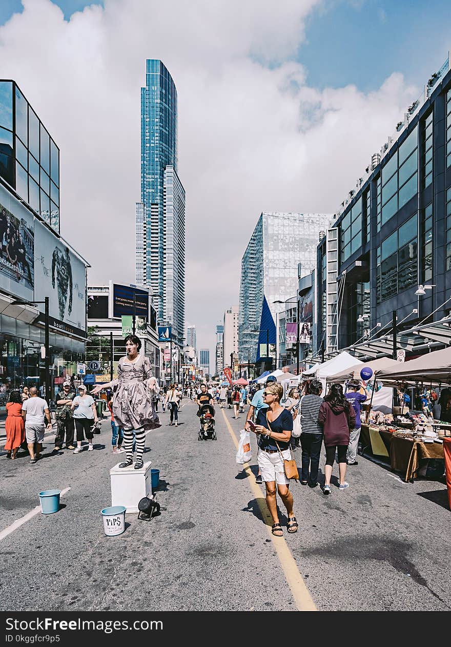 People in the Middle of the Street Under Blue Cloudy Skies