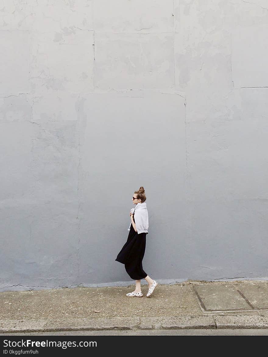 Woman Wearing Black Maxi Dress and Pair of White Flats Standing Beside Gray Wall