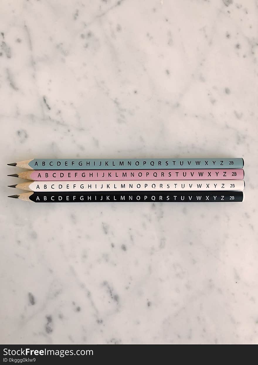 Photo of Four Pencils on Marble Tiles