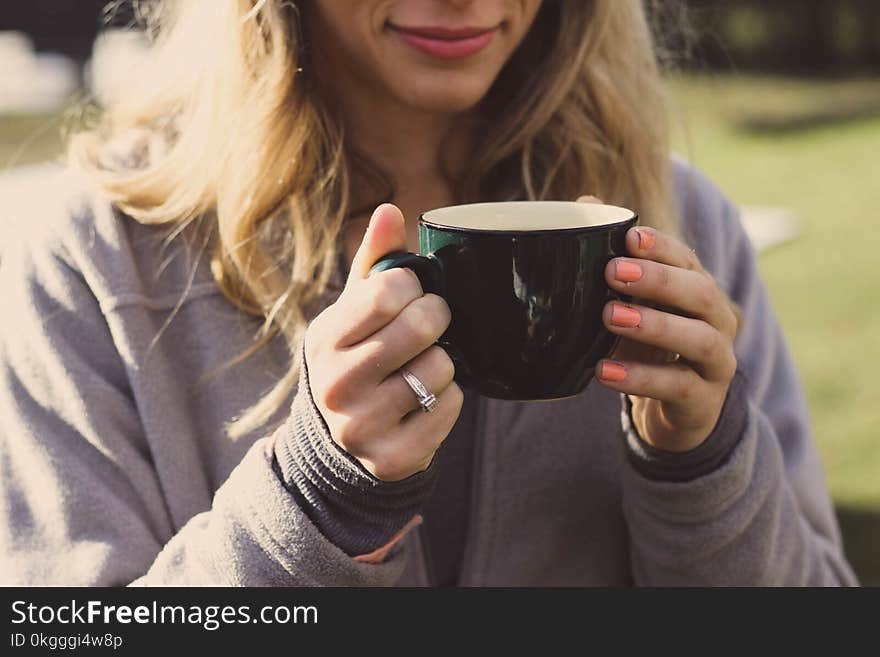 Woman Wearing Gray Zip-up Jacket Holding Ceramic Cup