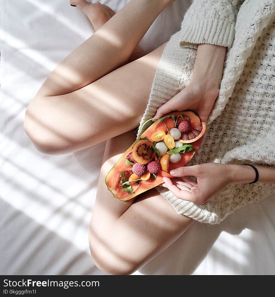 Person Holding Papaya Fruit on Bed