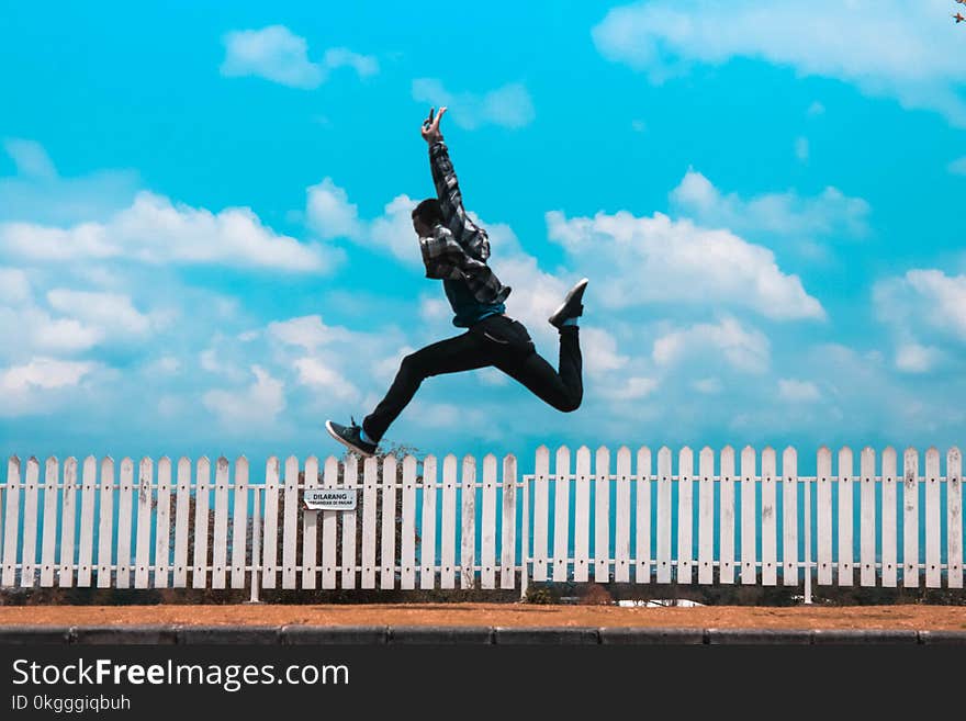 Man Jumping over White Fence