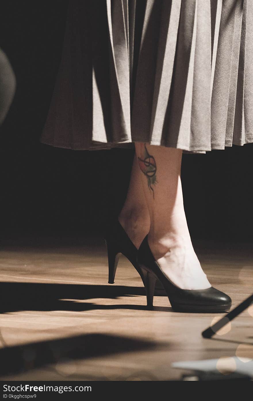 Woman in Black Heeled Shoes Standing on Brown Surface