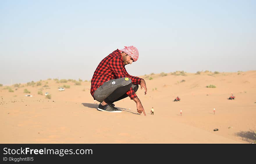 Man in Flannel Shirt Sitting on Sand