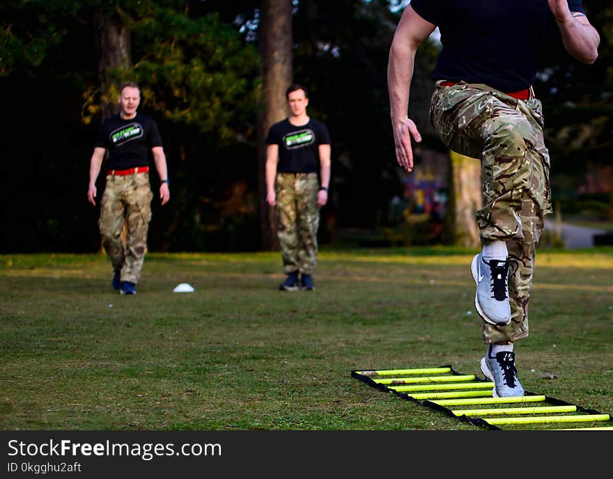 Three Men in Black Shirt and Camouflage Pants on Field