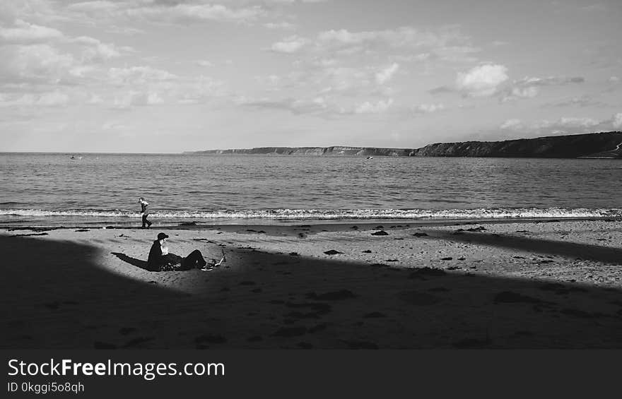 Grayscale Photo of a Man on Sand Near the Sea