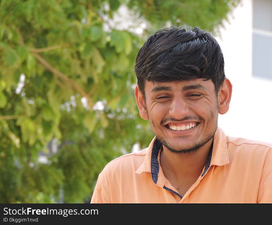 Man Smiles While Taking Photo Near Tall Tree at Daytime