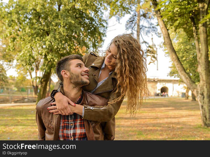 Man and Woman Wearing Wearing Brown Leather Jacket Near Green Leaf Tree