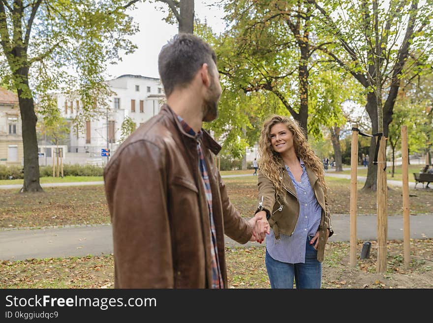 Man Holding Woman&#x27;s Hand Near Trees