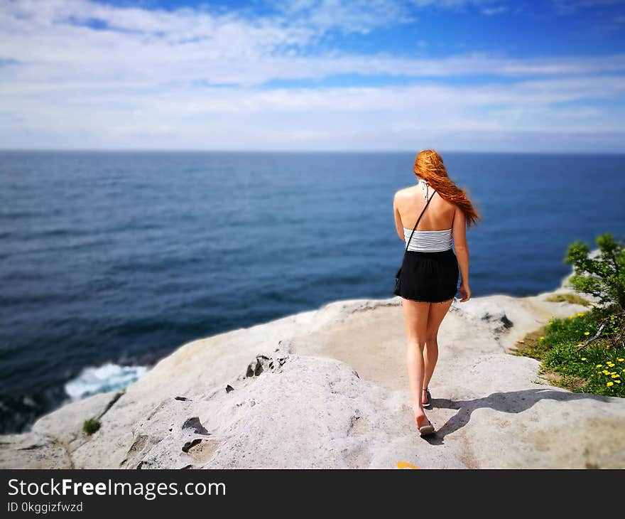 Woman Wearing Black Skirt Walking on Side of Cliff