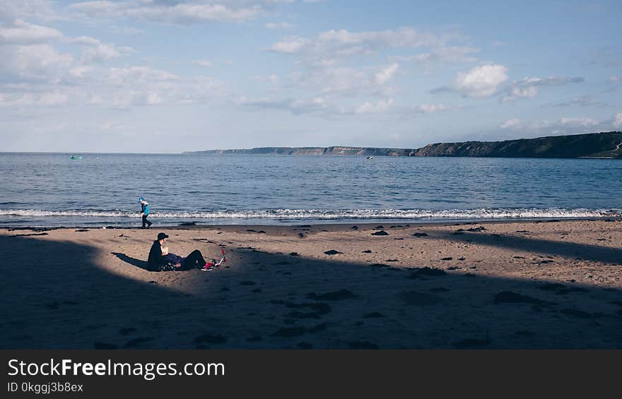 Person Walking Near Ocean Under White Sky