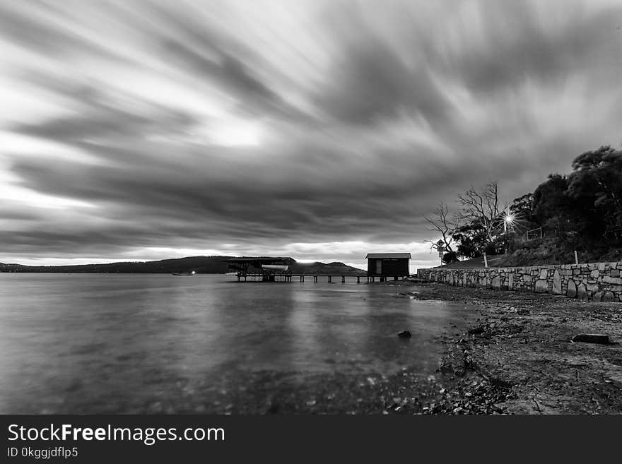 Time Lapse Photo of a House Near Body of Water in Grayscale