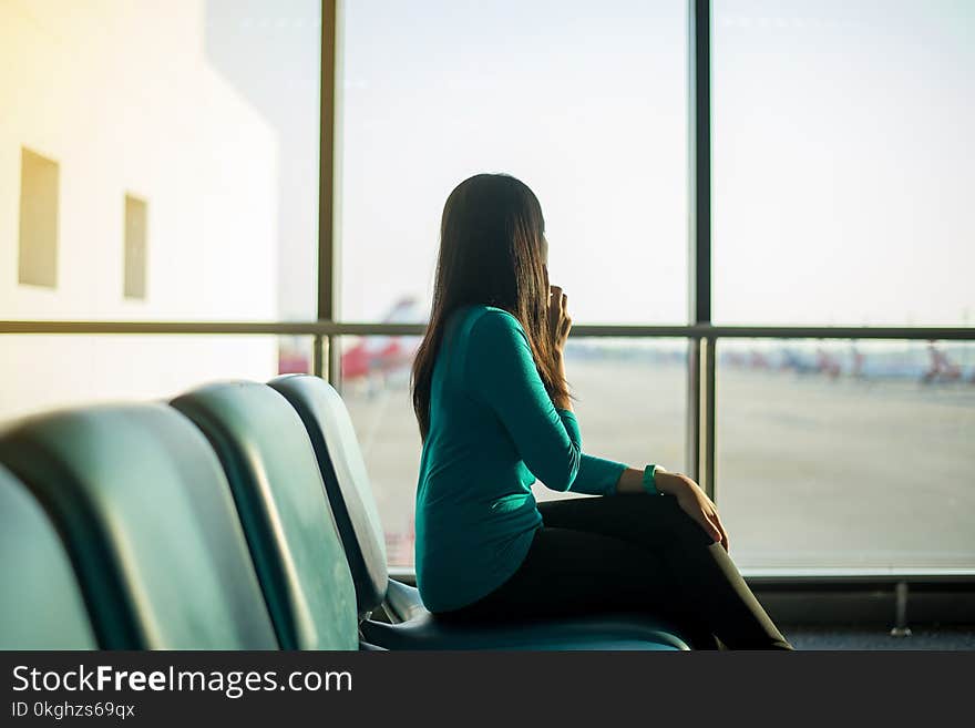 Asian woman passenger using smartphone and checking flight or online check in and travel planner at international airport terminal