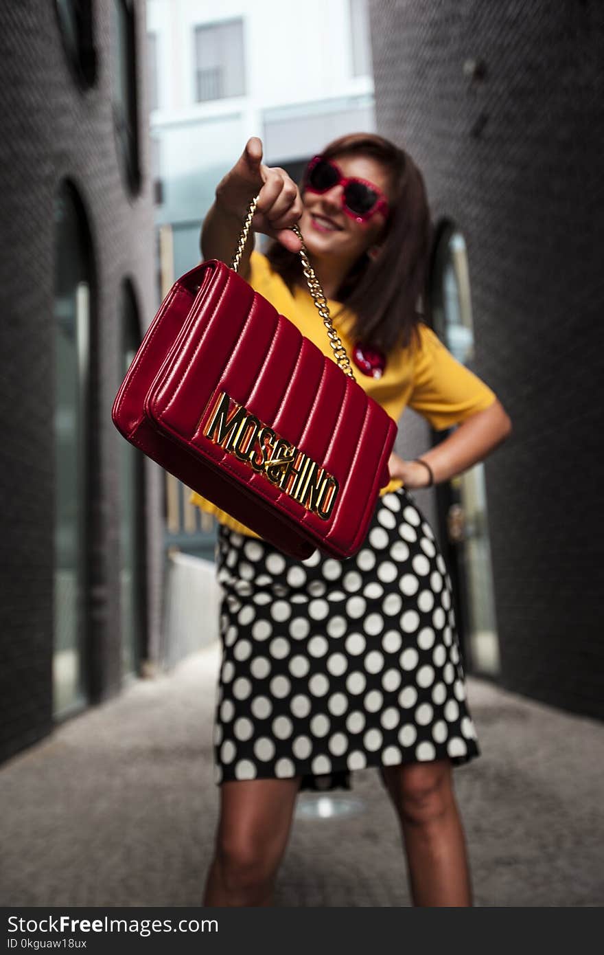 Woman Wearing Yellow Crew-neck T-shirt While Holding Red Handbag