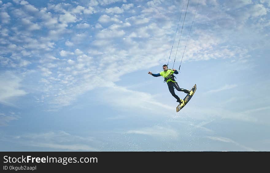 Man Wearing Green and Black Wetsuit Riding Wakeboard