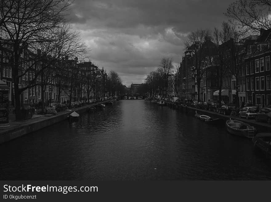 Grayscale Photography of River Near Buildings