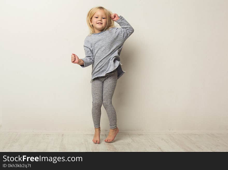 Beautiful casual little girl posing at white studio background. Full-length portrait of cute happy jumping kid, copy space. Beautiful casual little girl posing at white studio background. Full-length portrait of cute happy jumping kid, copy space