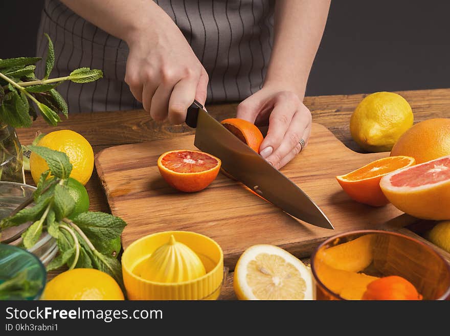 Female hands cutting citrus fruits on wooden board