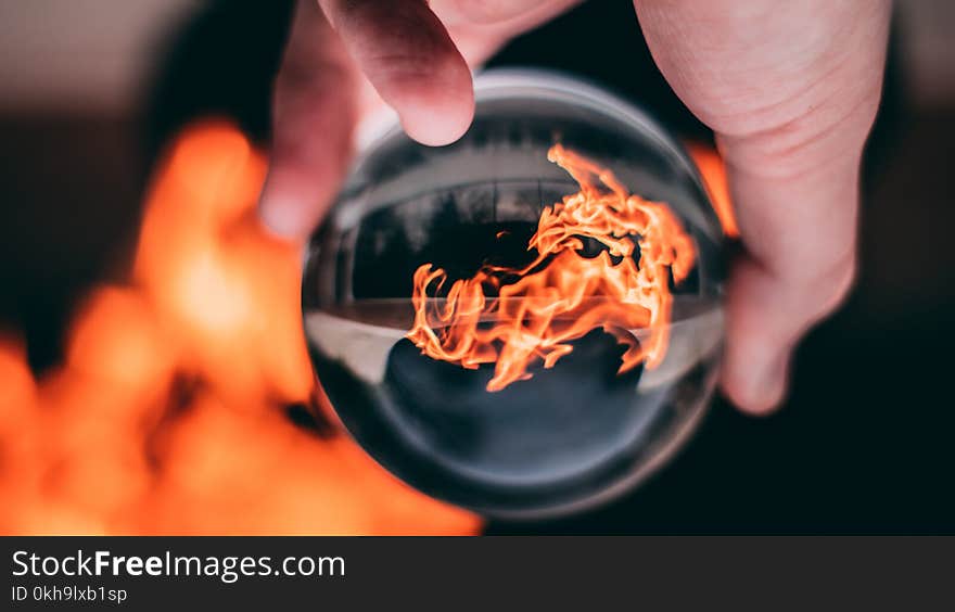 Person Holding Clear Glass Ball With Flame