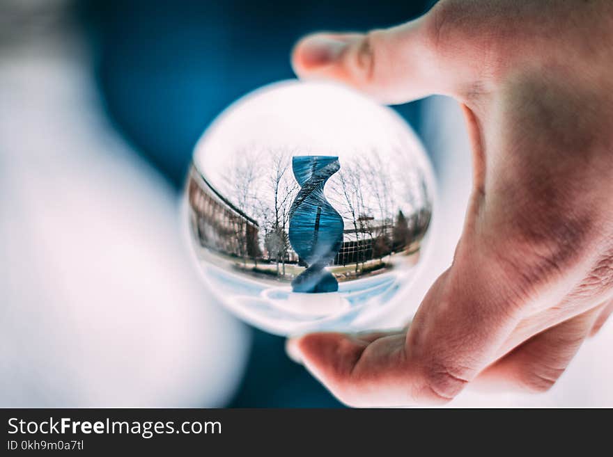 Person Holding Sphere Reflecting Dna-shaped Statue