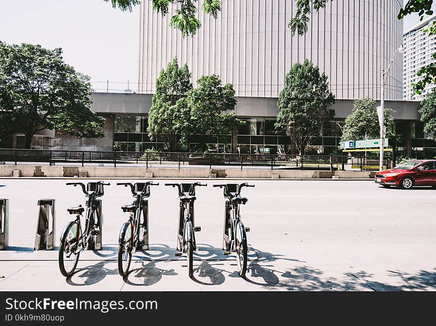 Four Black Parked Bicycles Near the Road