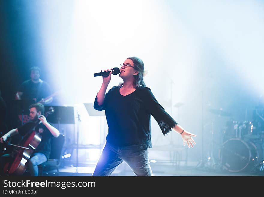 Woman Holding Microphone While Singing on Stage