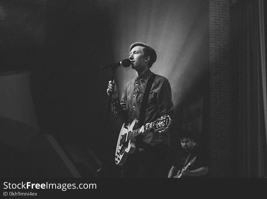 Grayscale Photography of Person Near on Pedestal Microphone