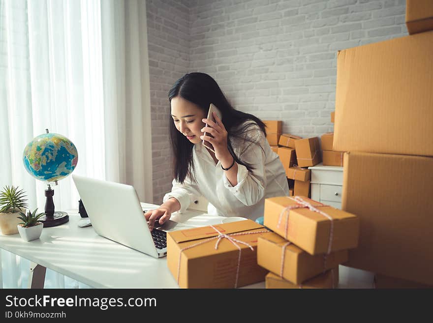 Woman Wearing White Dress Shirt Using Phone and Holding Laptop