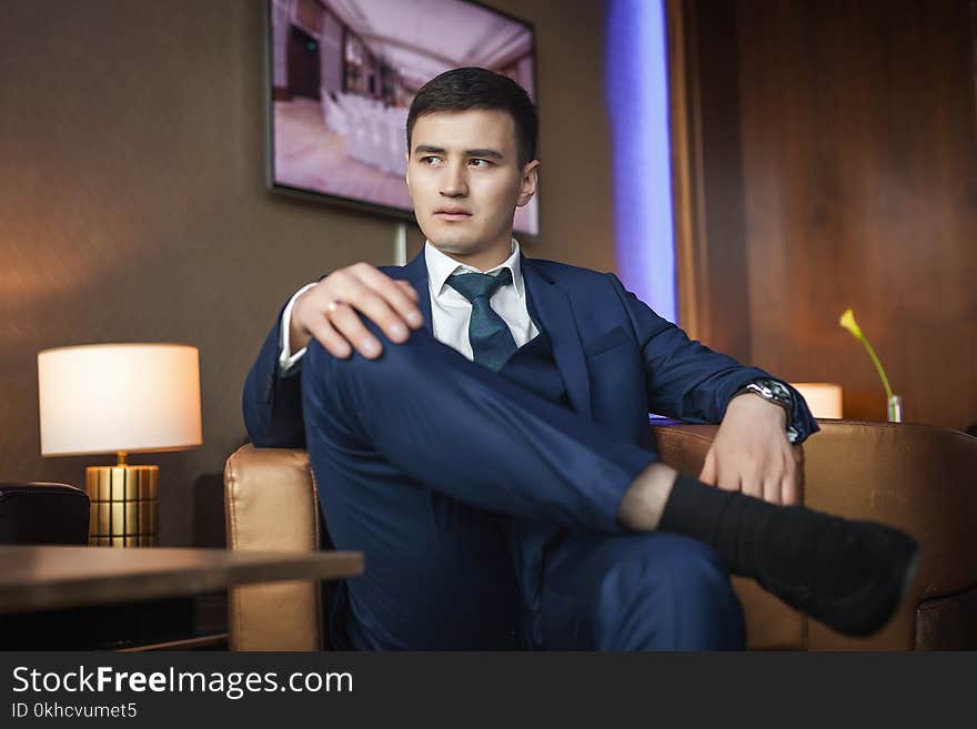 Asian Groom Sitting On The Chair In Hotel