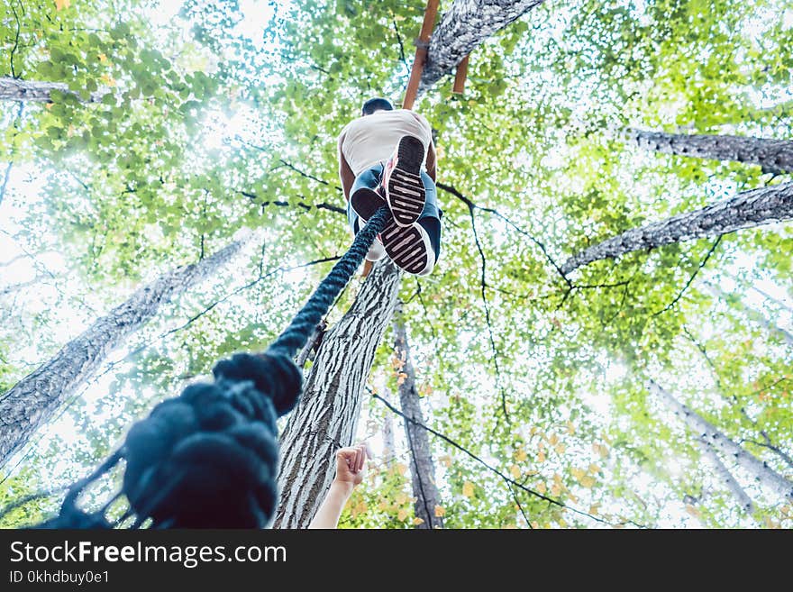 Very fit and athletic man climbing a rope