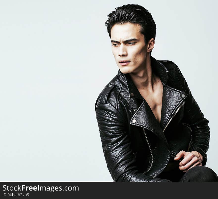 Young handsome man, leather jacked on naked torso, emotional posing, white background, modern guy, lifestyle people concept close up