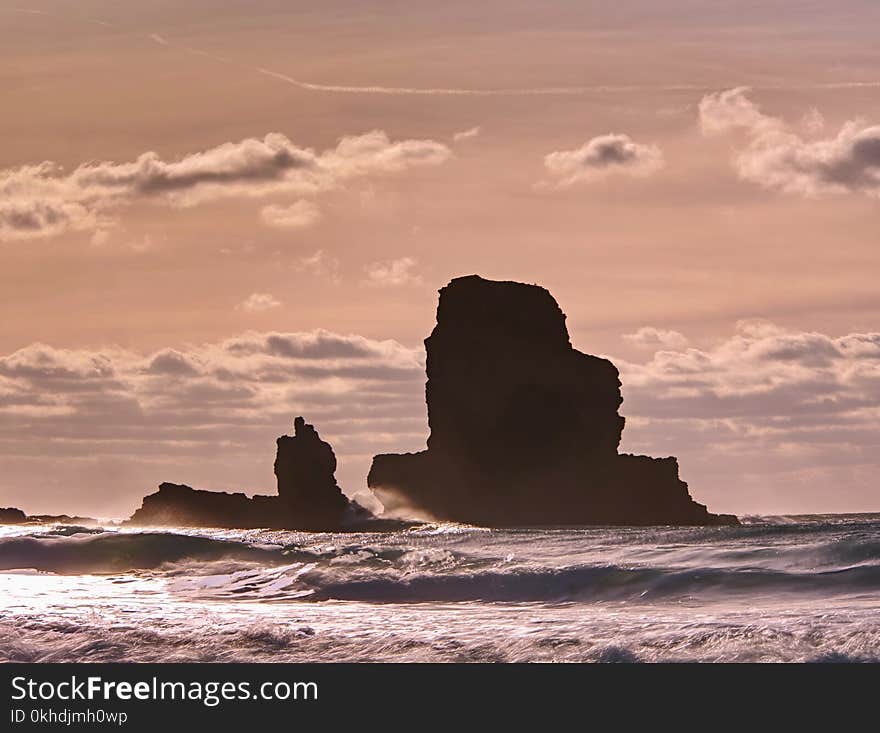 Amazing sunset, Talisker bay on the Isle of Skye in Scotland. Foamy sea, boulders and large cracked rocks with erosion marks. Rocky coastline with sea water