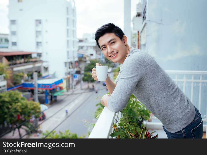 Handsome guy relaxing on a balcony, on a city background.