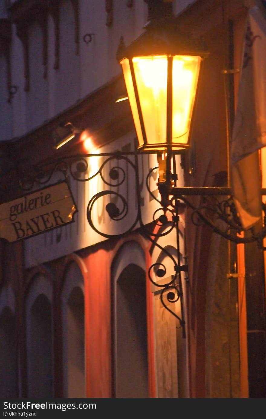 An old street lamp illuminates the street at dusk. An old street lamp illuminates the street at dusk.