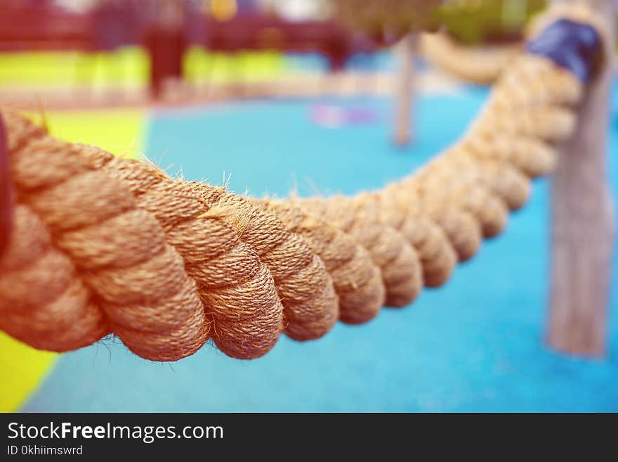 Thick braided rope on the Playground for children. Tied to poles. Photographed along. The background is blurred.