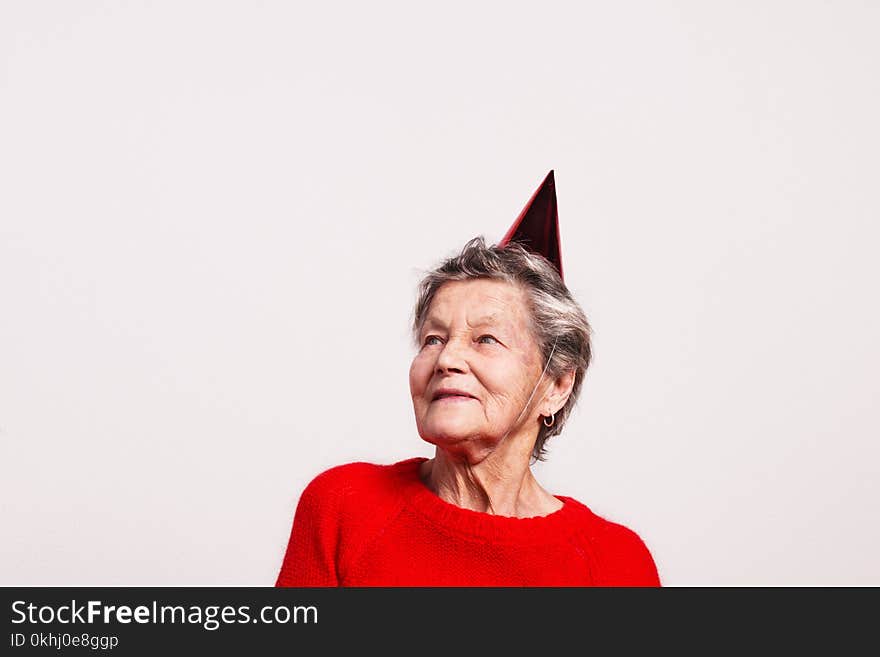 Portrait of a senior woman in studio on a gray background. Party concept. Copy space.