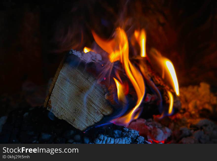 Bright colorful flame, burning wood at the fireplace. Firewood brick at the fire, closeup.