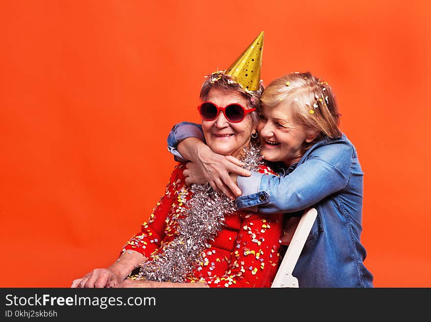 Portrait of a senior women in studio on a red background. Party concept. Close up.