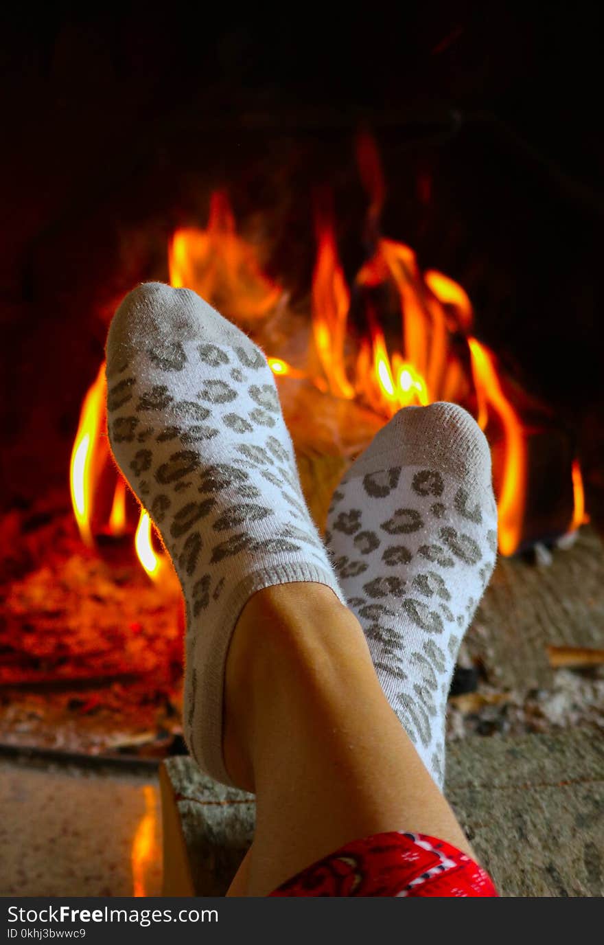 Burning Wood At The Fireplace, Female Legs In Socks Warming Up.