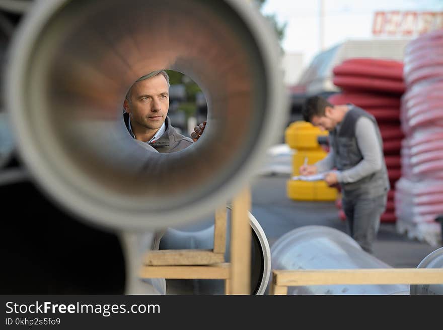 Male supervisor examining large pipe at construction site